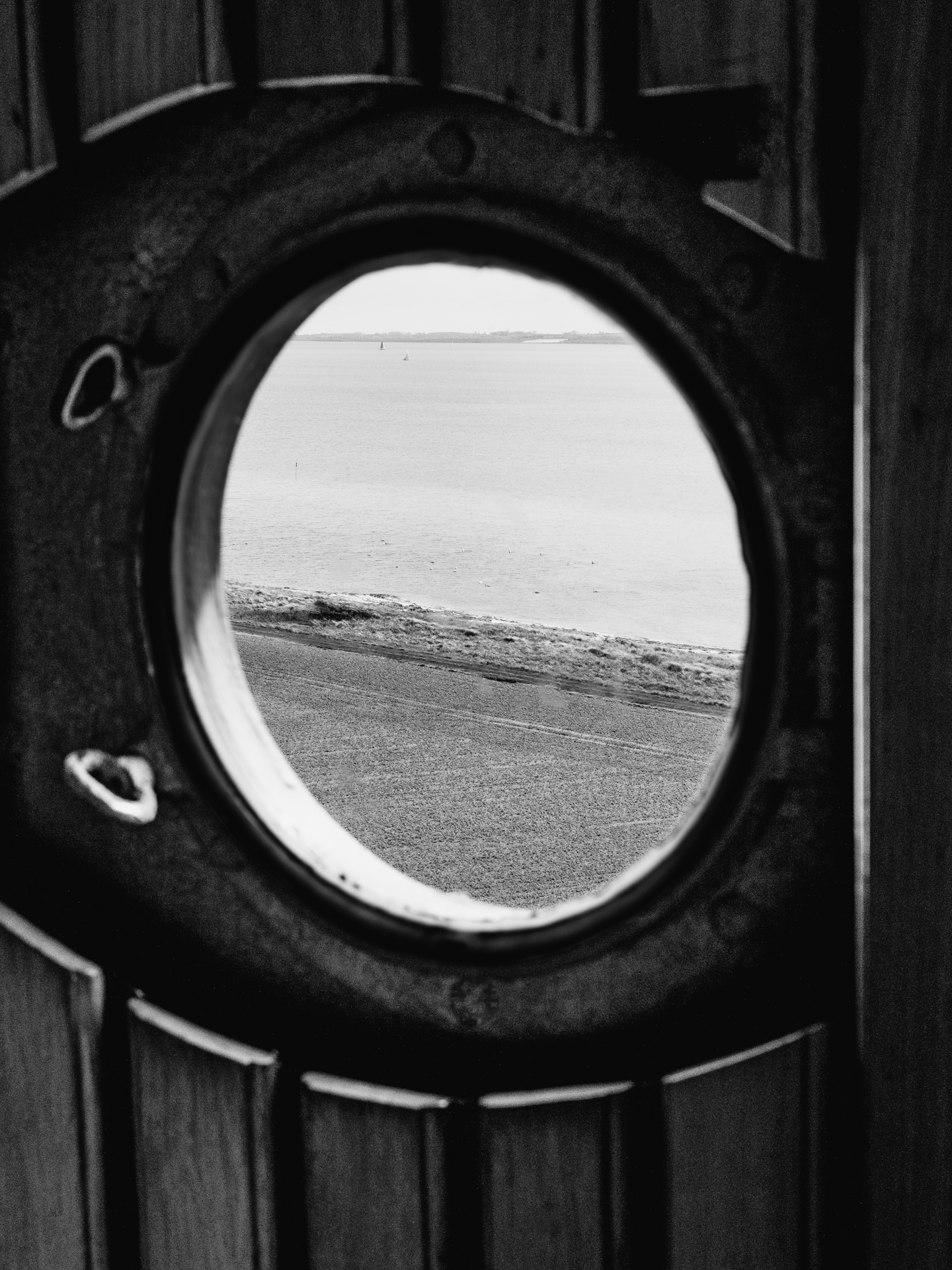 Schwarzweiß-Fotografie eines Bullauges auf dem Flügger Leuchtturm